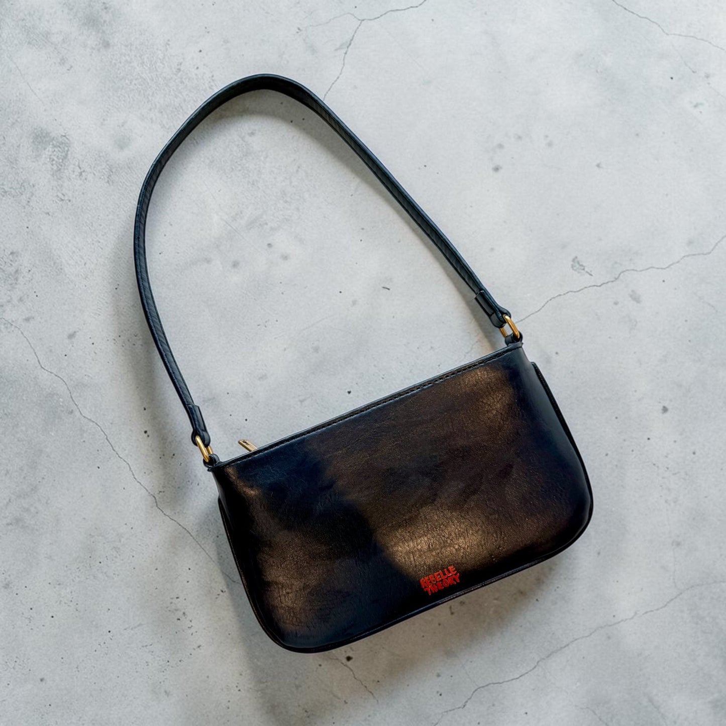 Black handbag on a gray concrete surface