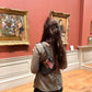 Woman looking at paintings in an art gallery with a red wall, wearing a handprinted jacket that features a still life painting with apples.