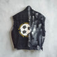 A black washed denim vest shown from the back, featuring a large graphic print of a soccer ball with the words 'Awareness, Loyalty' and 'Gert D'Armony' in yellow text, laid flat on a light gray concrete surface.